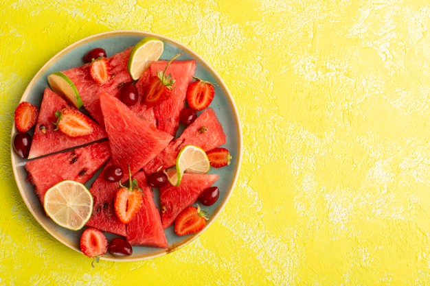 top-view-sliced-watermelon-with-sliced-lemons-strawberries-yellow-surface_140725-29891
